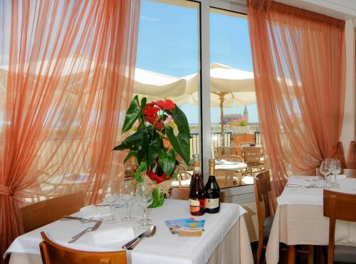 una mesa con un jarrón de flores rojas. en Hotel Giacomazzo en Caorle