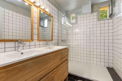 een wit betegelde badkamer met een wastafel en een spiegel bij Beautiful air-conditioned house and heated pool in La Celle-sous-Gouzon