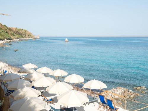 un grupo de sombrillas y sillas blancas en una playa en San Domenico Village, en Fitili