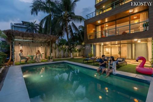 Ekostay Gold- Salt Water Villa I Sea View I 200 meters from Beach في كاندوليم: زوجان يجلسان بجوار حمام سباحة في منزل