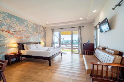 a bedroom with a bed and a tv and a couch at Samprasob Resort in Sangkhla Buri