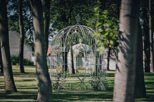 a metal bird cage in a park with trees at Hotel Panství Dlouhá Lhota in Dlouhá Lhota