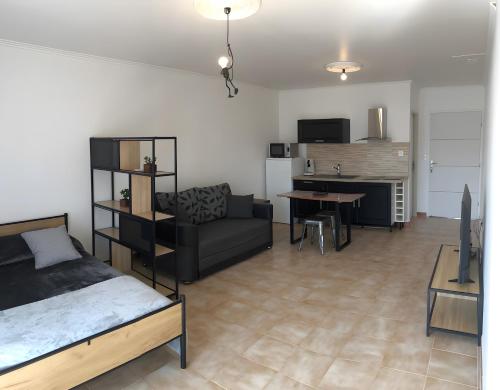 ein Wohnzimmer mit einem Bett, einer Couch und einem Tisch in der Unterkunft Gîtes Villa Beau Soleil Agde in Agde