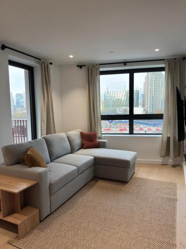 a living room with a gray couch and large windows at 02 Arena, Thames Riverside Retreat in London
