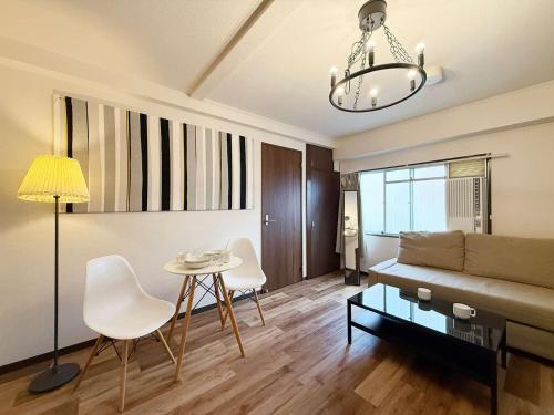 a living room with a couch and a table and chairs at Hottie - 1 Bedrm Apt 5mins from Hiroshima Sta 5ppl 302 in Hiroshima