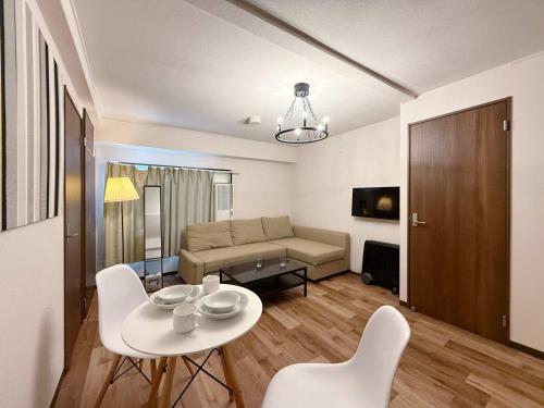 a living room with a couch and a table and chairs at Hottie - 1 Bedrm Apt 5mins from Hiroshima Sta 5ppl 302 in Hiroshima