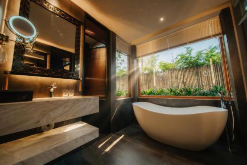 a bathroom with a large tub and a window at Lynntimes Thanh Thủy Wellness Hotel & Resort in La Phu