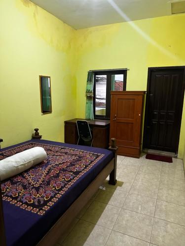 a bedroom with a bed and a desk and a window at The wilsian - Syariah guest house in Sengkaling