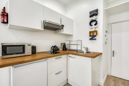 une cuisine avec des armoires blanches et un micro-ondes dans l'établissement Sweett - Aboukir II, à Paris