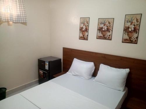 ein Schlafzimmer mit einem Bett mit weißen Laken und drei Bildern an der Wand in der Unterkunft Résidence Keur Mame Seye 4 in Dakar