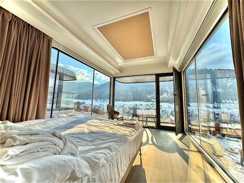a bedroom with a bed and large glass windows at Capsule & Enesai Hotels Karakol in Karakol
