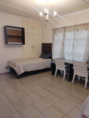 een slaapkamer met een bed, een tafel en stoelen bij Prior guest house in Pinetown