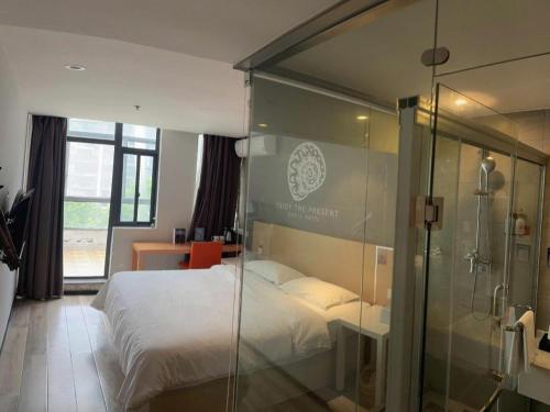 a bedroom with a bed and a glass shower at Shell Nanjing Jiangning District University City Hotel in Chunhua
