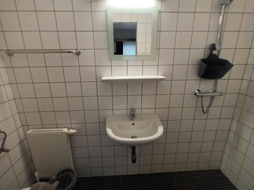 Baño de azulejos blancos con lavabo y espejo en Pension Waldfrieden, en Steinhaus am Semmering