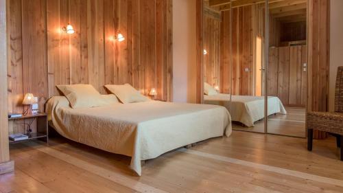バン・レ・バンにあるChambre Printanière, Maison d'hôtes La Landreの木製の壁のベッドルーム1室(ベッド2台付)