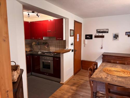een keuken met rode kasten en een houten tafel bij L'Atelier du Temps - Il Sogno di GI in Courmayeur
