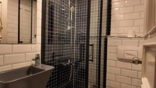 een badkamer met een wastafel en een douche met zwarte tegels bij Hotel Zurich Oldtown in Antalya