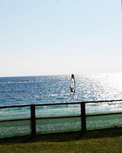 a sail boat in the water near a fence at Panorama Beach House, 5 meters to the sea in Perivolia
