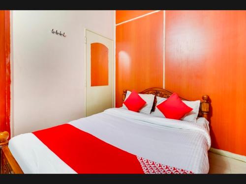 a bed with red and white sheets and red pillows at Hotel RJ Madurai in Madurai