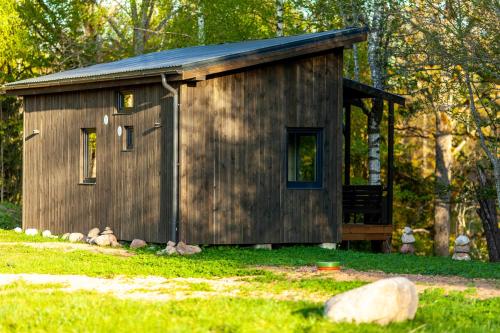 a small wooden cabin in the grass in a yard at Holiday cabin 'OAK' in Salacgrīva
