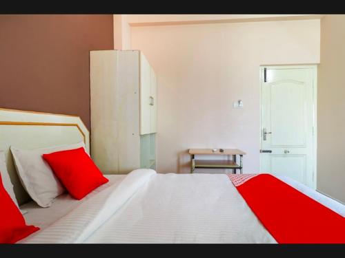 a bedroom with a large white bed with red pillows at Hotel RJ Madurai in Madurai