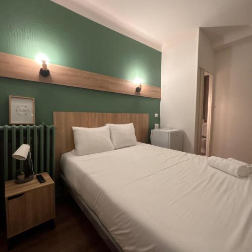 Central Hôtel في سانت-بريست: غرفة نوم بها سرير أبيض وجدار أخضر