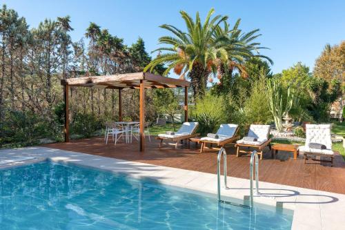 een zwembad met een prieel en een tafel en stoelen bij Coral Tree Luxury Villa in Ialyssos