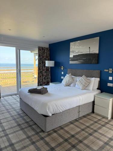 a bedroom with a large bed with a blue wall at Poseidon's in Lossiemouth