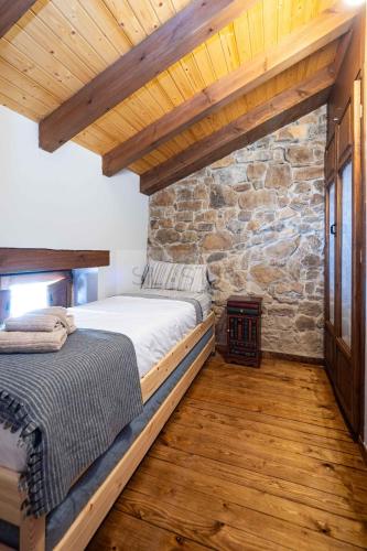 a bedroom with a bed and a stone wall at La Casina del Alba in Campiellos