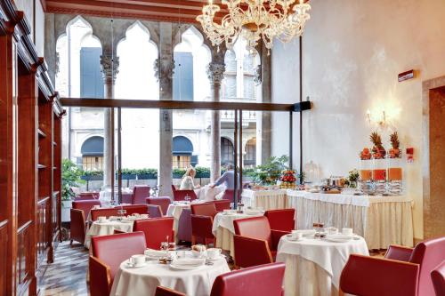una sala da pranzo con tavoli, sedie e lampadario a braccio di Hotel Donà Palace a Venezia