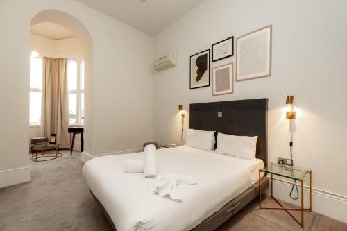 een slaapkamer met een groot wit bed en een tafel bij Kensington House Hotel in Londen