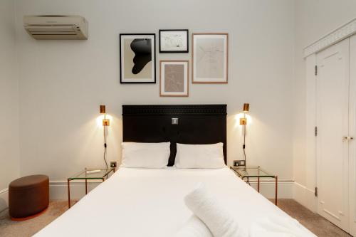 een slaapkamer met een groot wit bed met twee lampen bij Kensington House Hotel in Londen