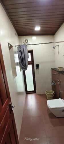 a bathroom with a toilet and a sink and a window at BharathaPuzha Resort in Kārakkād