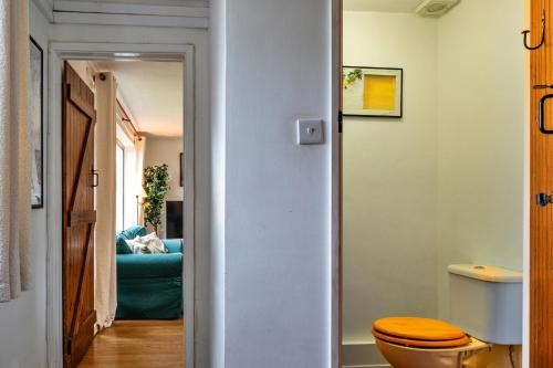 a bathroom with a toilet and a blue couch at Finest Retreats - Cricketers Cottage in Alderley