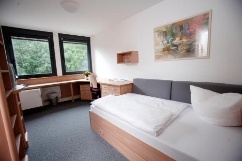 een slaapkamer met een bed, een bureau en ramen bij Laerholz 84 in Bochum