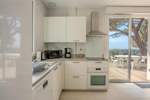 a kitchen with white cabinets and a view of the ocean at Villa Germaine les pieds dans l'eau in Andernos-les-Bains