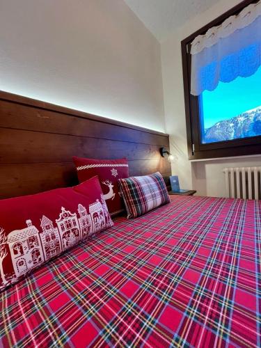 a bedroom with a red bed with a large window at Casa Lilly in Folgarida