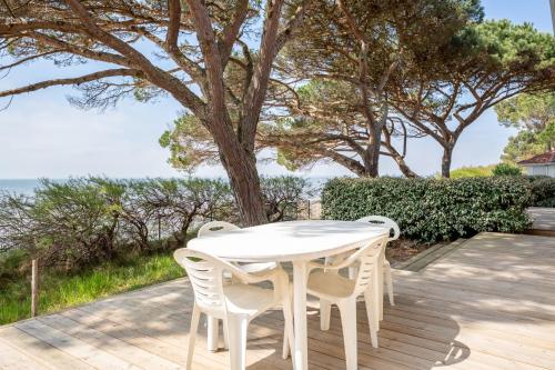 a white table and chairs on a deck with the ocean at Villa Germaine les pieds dans l'eau in Andernos-les-Bains