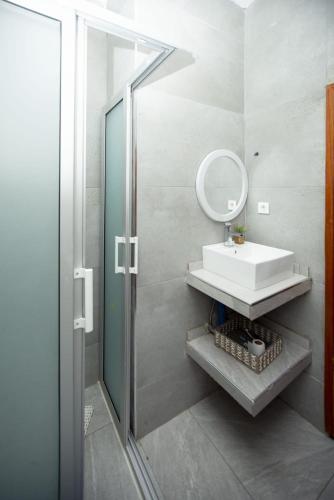 a bathroom with a sink and a mirror and a shower at Vila Luísa Bilene in Vila Praia Do Bilene