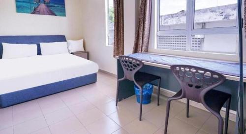 a bedroom with a bed and a desk and a window at Station Hotel Klang in Klang