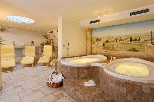 a large bathroom with two tubs and a painting at Landhaus Hotel Kristall in Marlengo