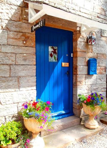 a blue door on the side of a stone building with flowers at Riverside Bed & Breakfast in Bainbridge