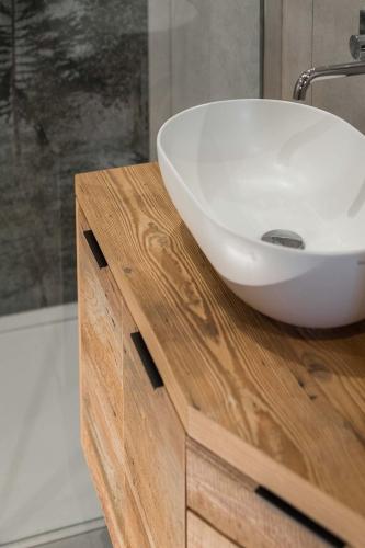 a white sink on a wooden counter in a bathroom at Suite Chalet Stella Margherita in Passo San Pellegrino