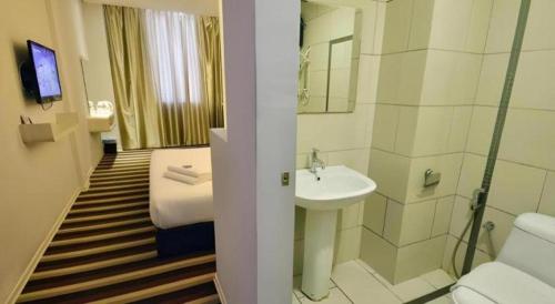 a hotel room with a bathroom with a bed and a sink at First Residence Hotel Kemaman in Kampong Gong Pauh