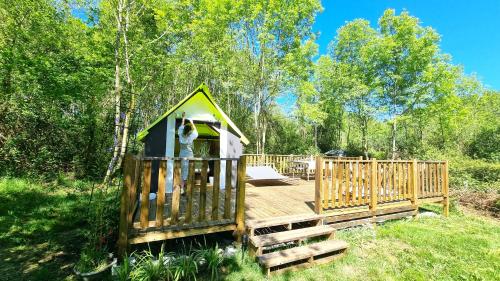 a small house with a wooden deck in the woods at Logements Insolites, Les Rêves d'Ambre 