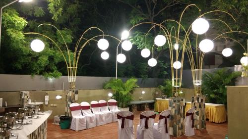 a banquet hall with white tables and chairs and lights at Hanu Reddy Residences Poes Garden in Chennai
