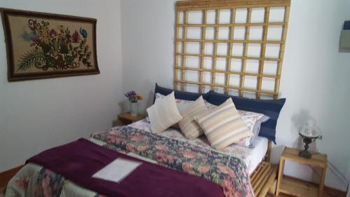 um quarto com uma cama com almofadas em Maison de la Montagne em Petrópolis