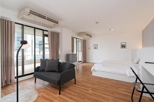 um quarto branco com uma cama e uma cadeira em Stylish Twin BR w Ensuite Bath & Relaxing Tub BTB7 em Banguecoque