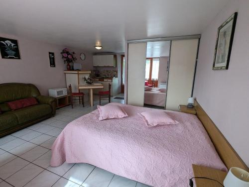 a bedroom with a pink bed and a living room at Chambre d'hôtes du Moineau in Le Val-dʼAjol
