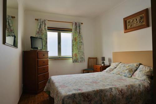 a bedroom with a bed and a television and a window at Casa da Praia - Vista Mar in Ericeira